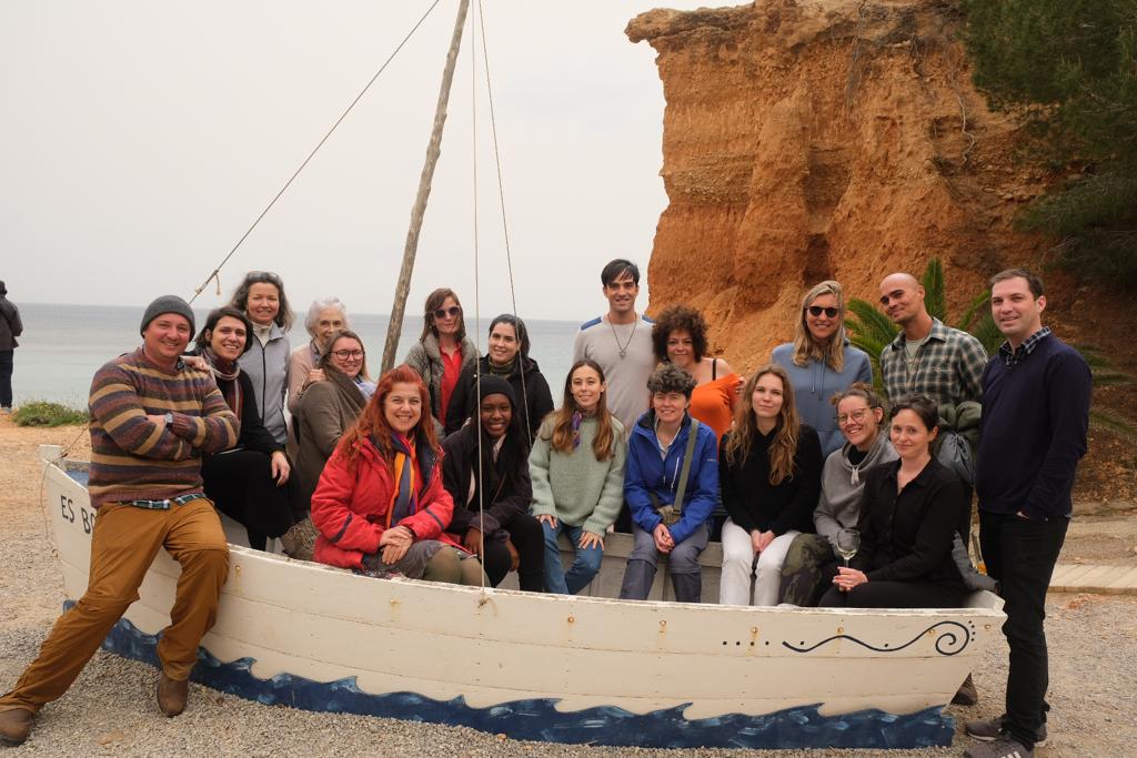 A group of people in a small wooden boat on the sandy shore