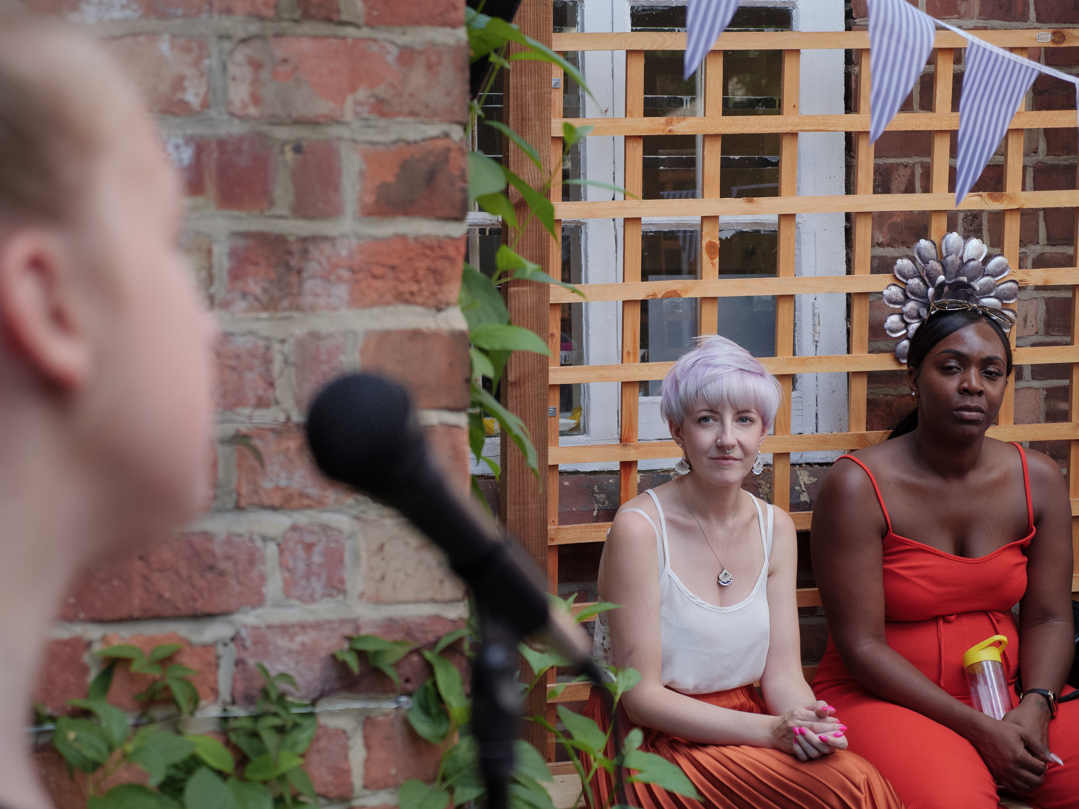 Two people watching someone at a microphone