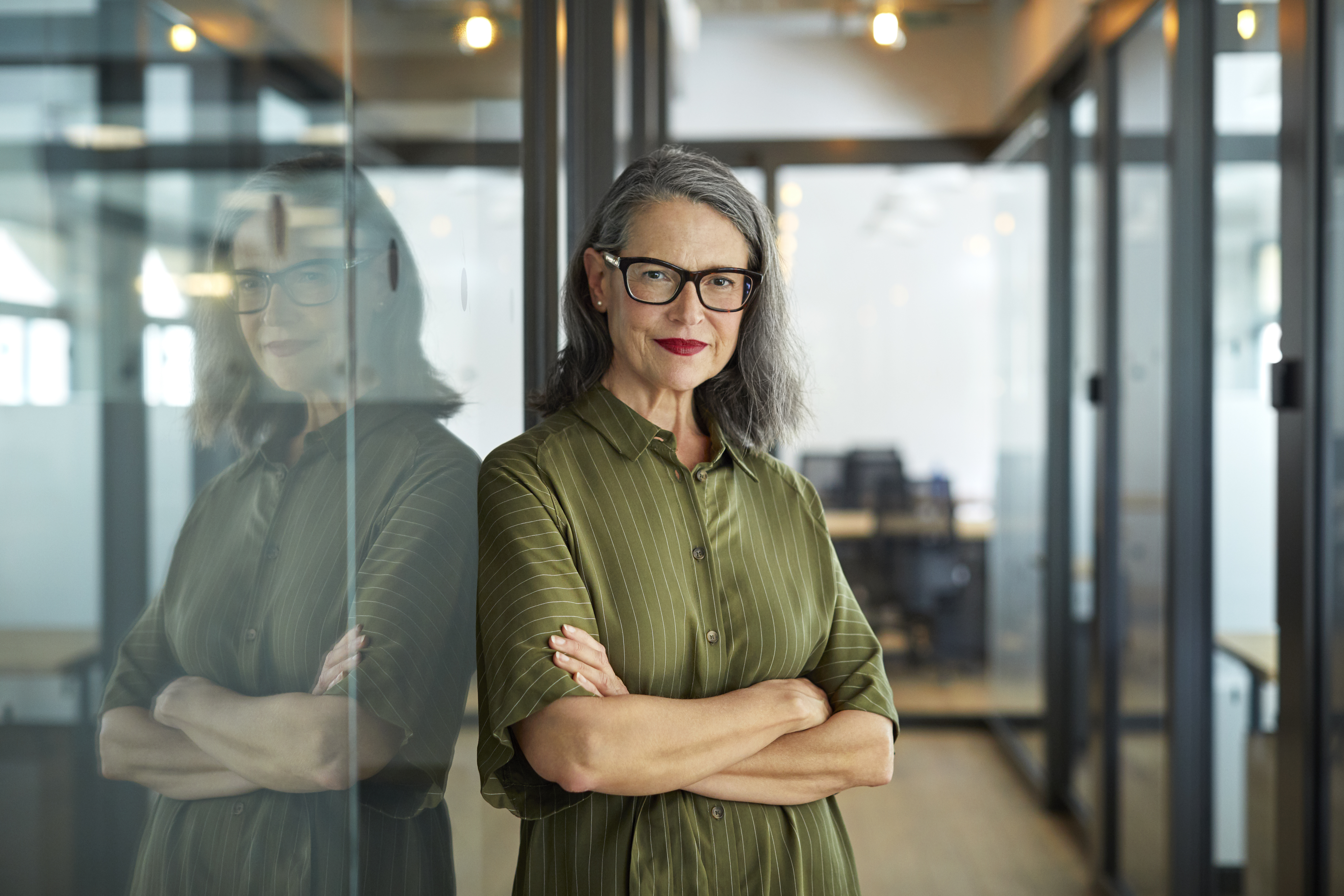 Older woman leaning against a glass office wall