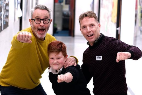 One boy and two men looking at the camera in superhero poses