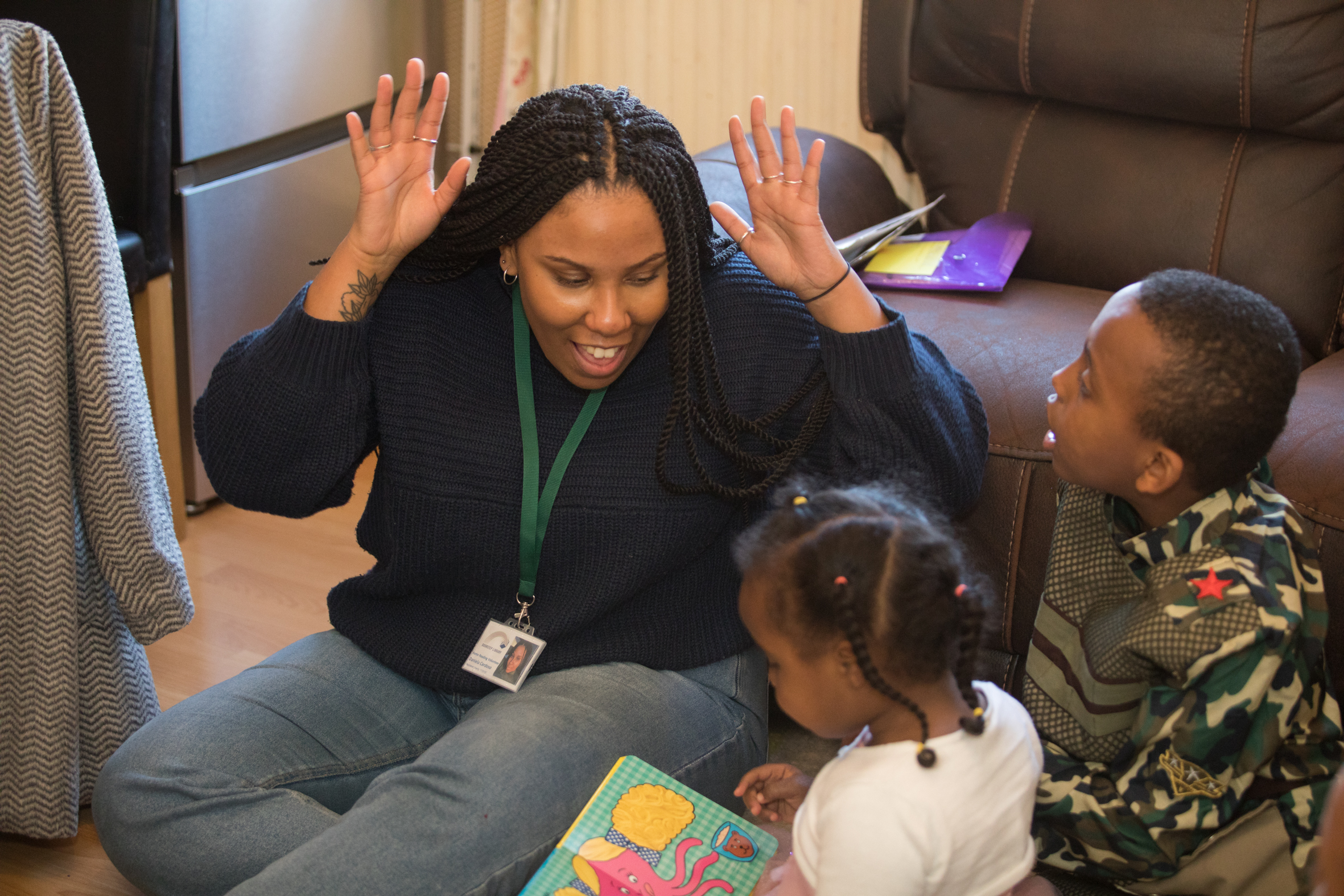 A volunteer helping two children read