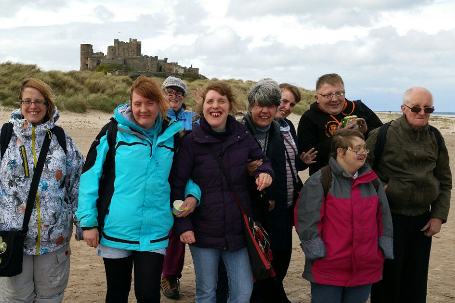 A group of people posing for the camera on a beach in front of a castle