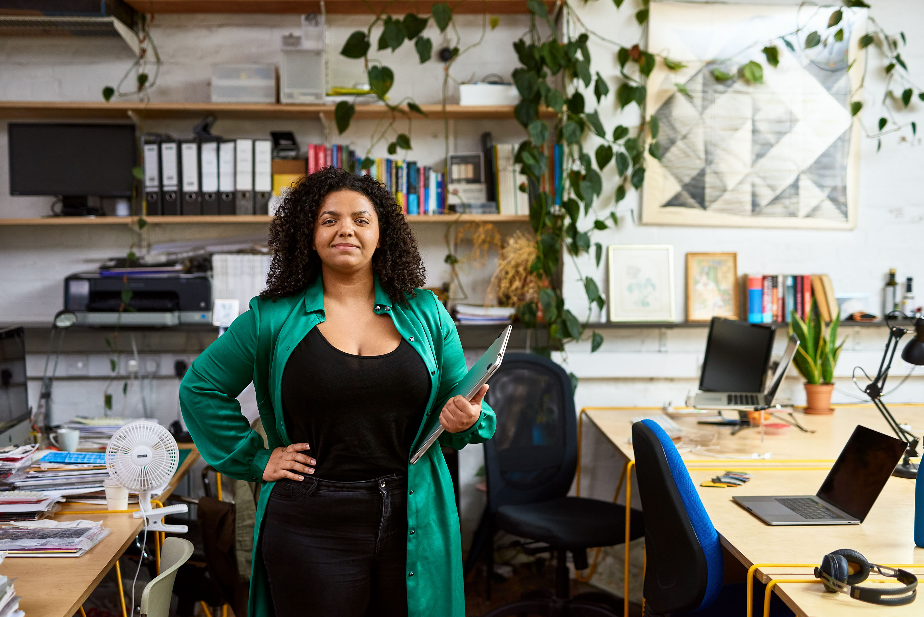 Mixed race woman standing in an office holding a laptop