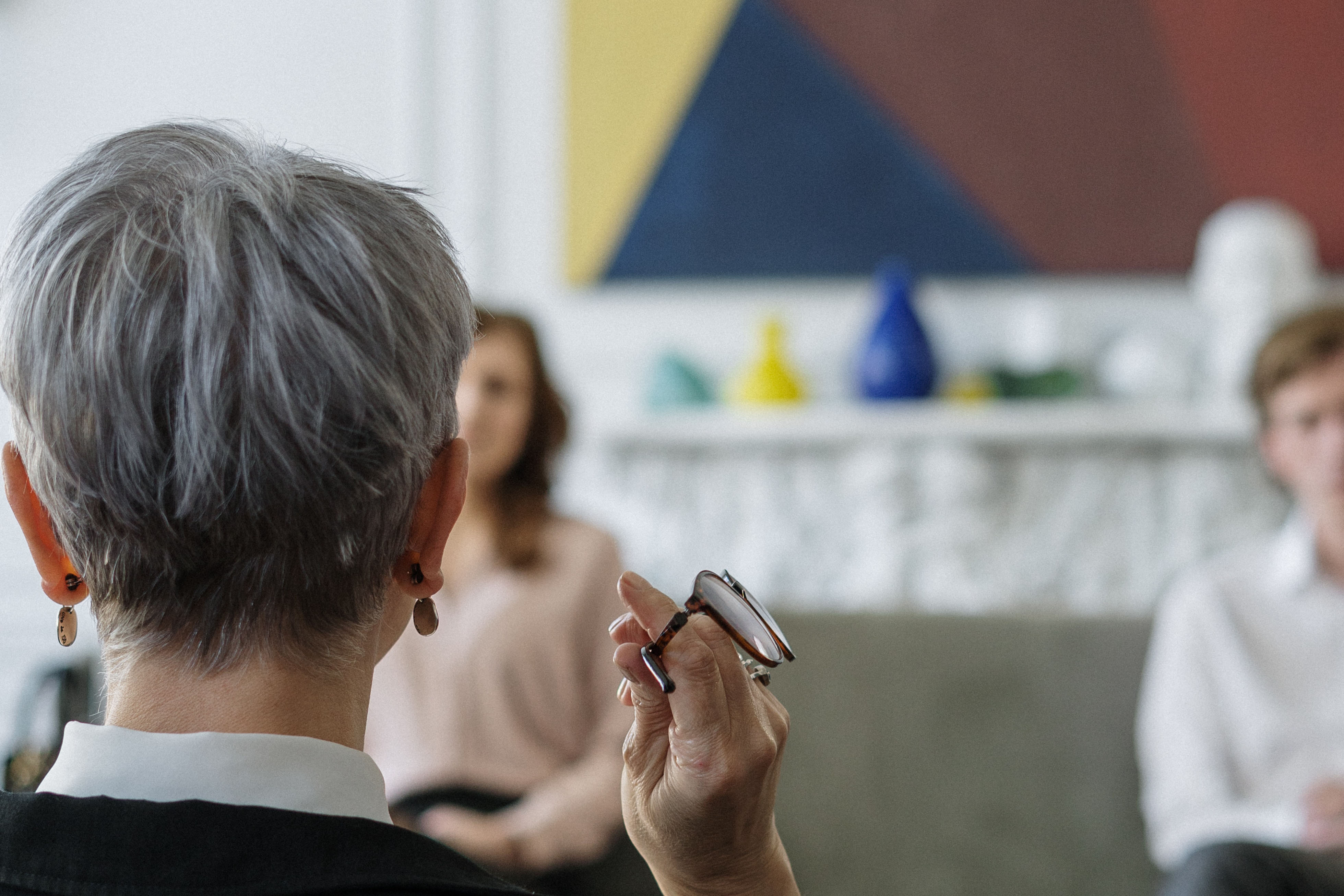 The back of an older woman's head who is holding glasses