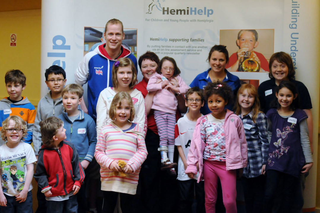 A group of children and adults in front of a charity banner