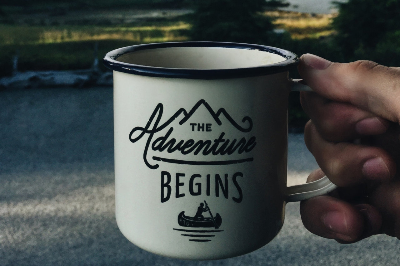 A white mug with 'the Adventure begins ' written on it