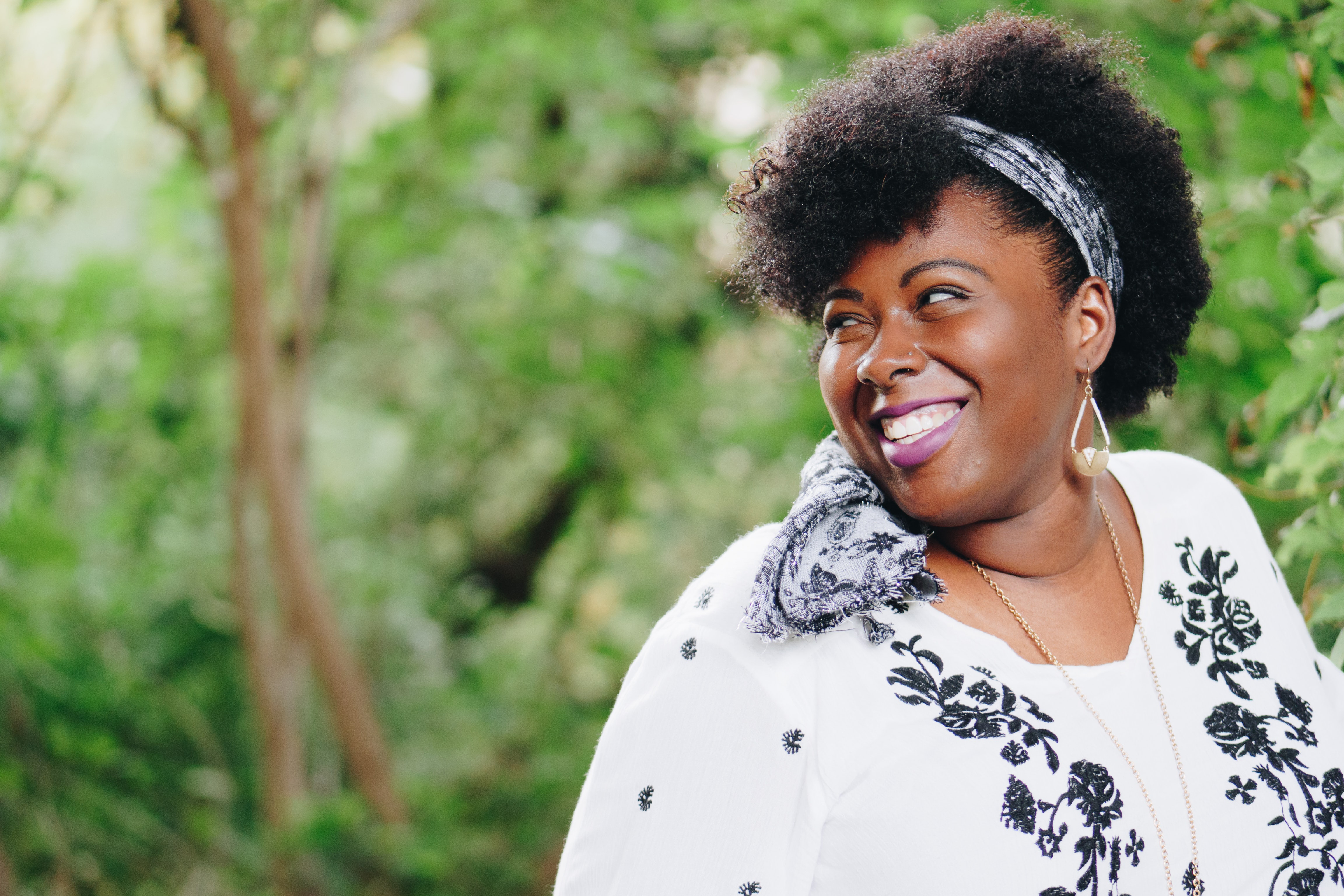 A black women in front of trees looking behind her