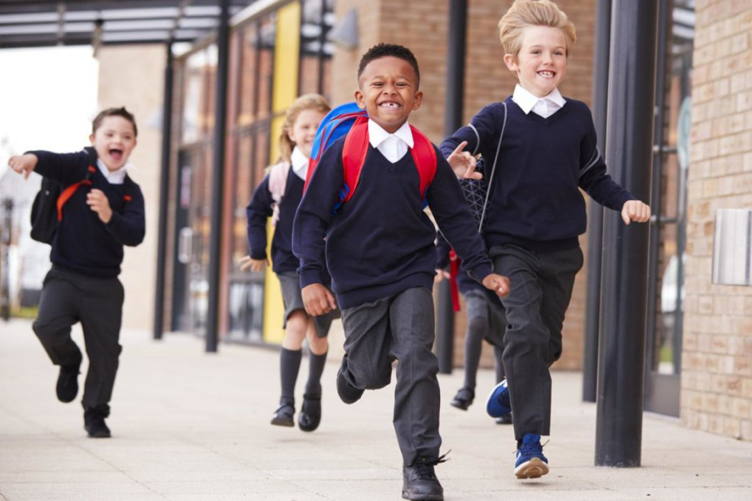 A group of school children running towards the camera