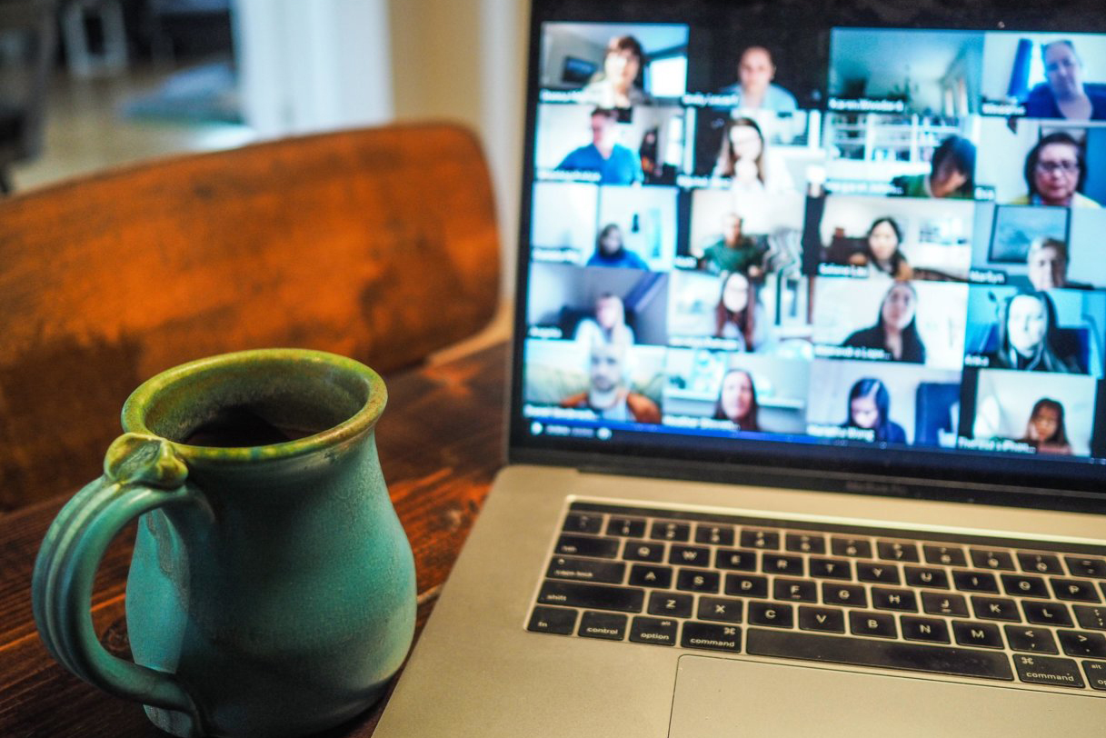 A laptop with a zoom meeting and a cup of tea next to it