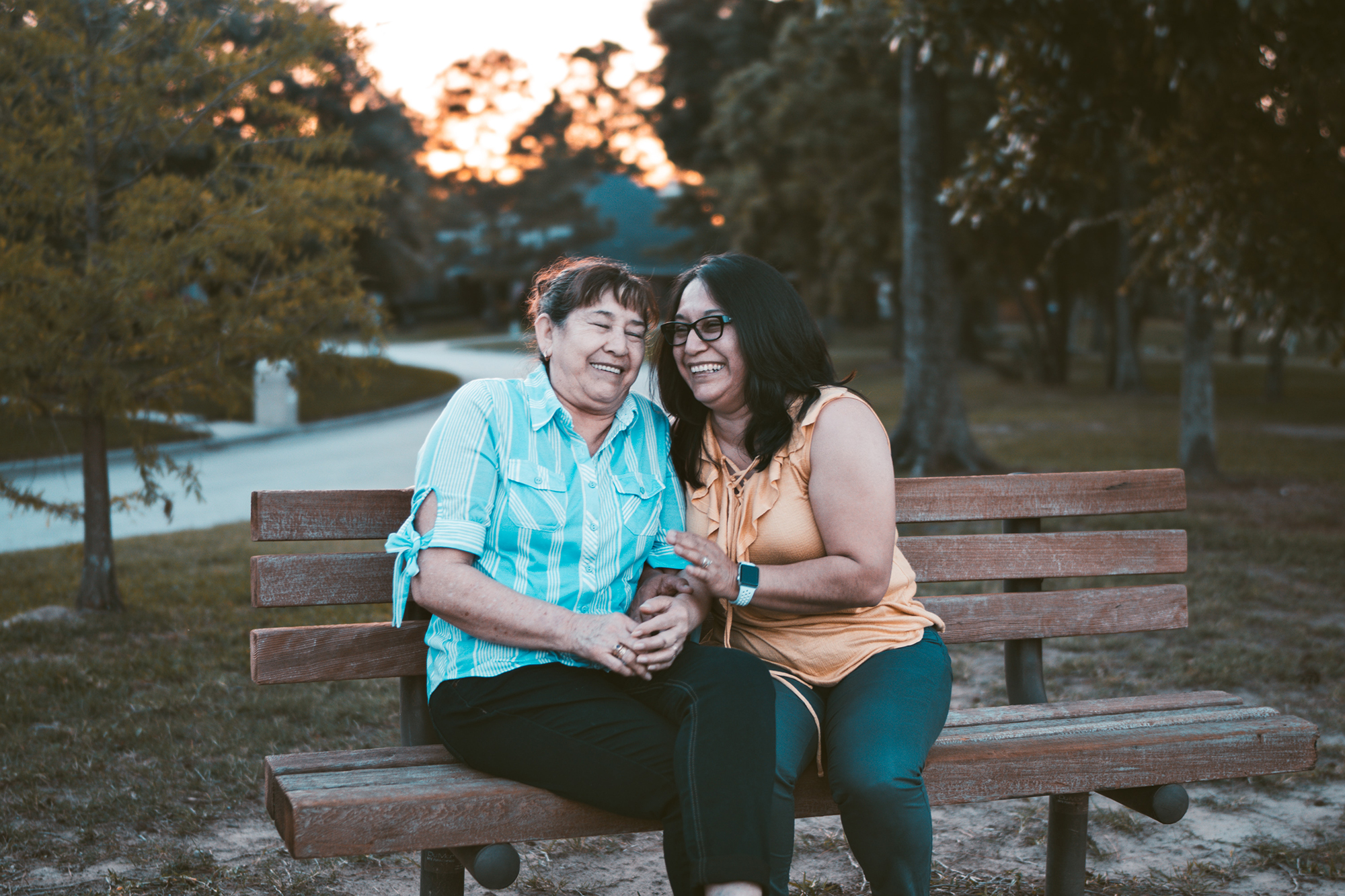 Two people laughing on a bench