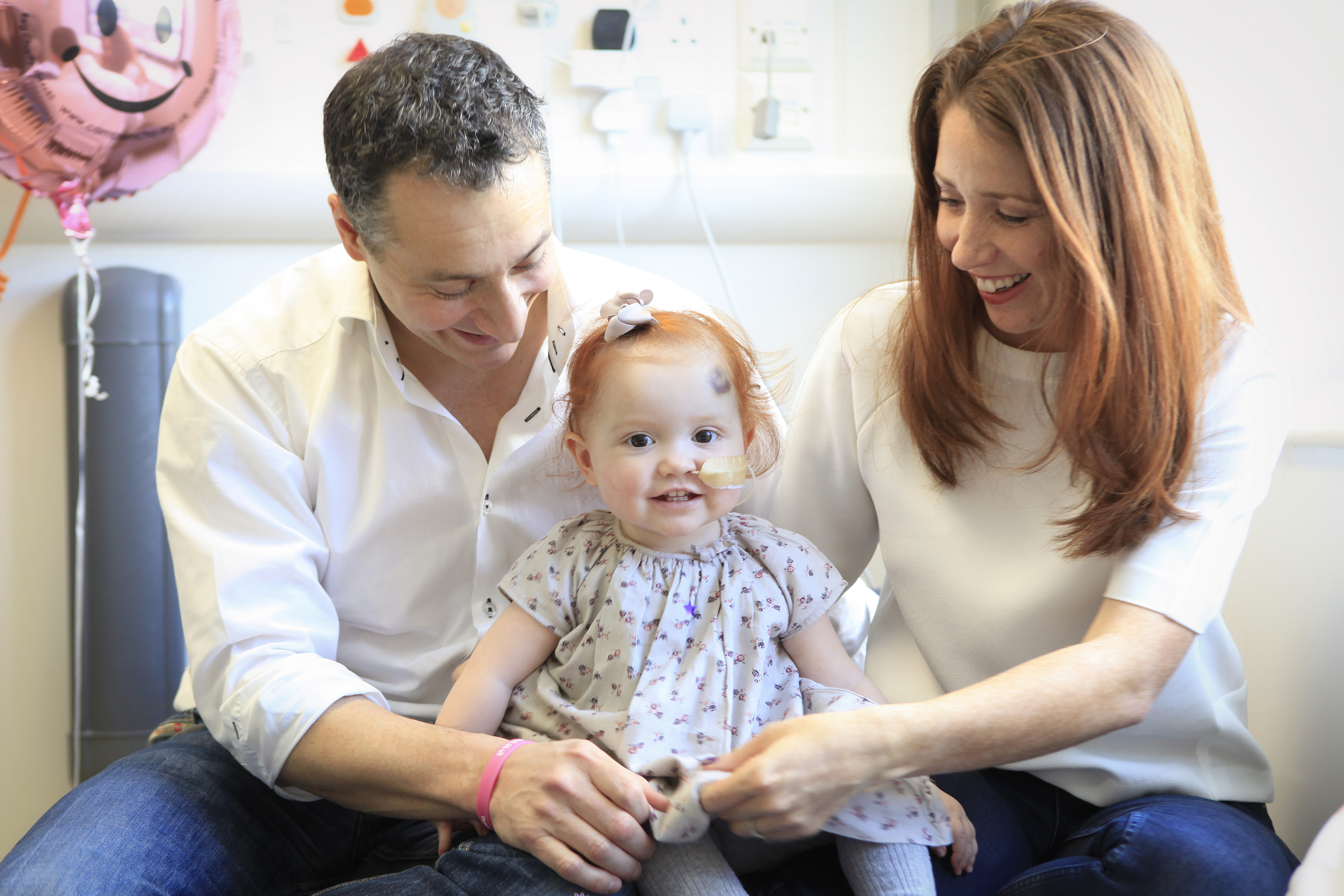 Family photo of baby Margot Martini with her parents on either side of her in the hospital