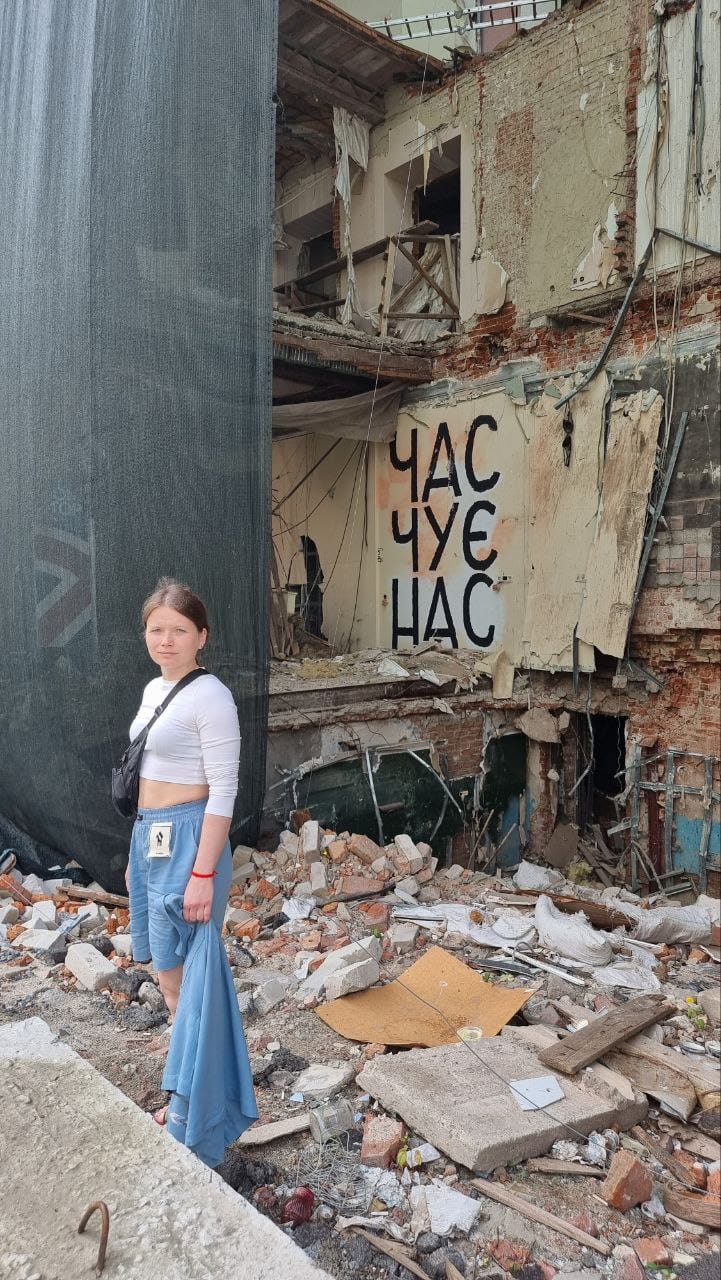 yougn woman standing in front of slogan that says time hears us