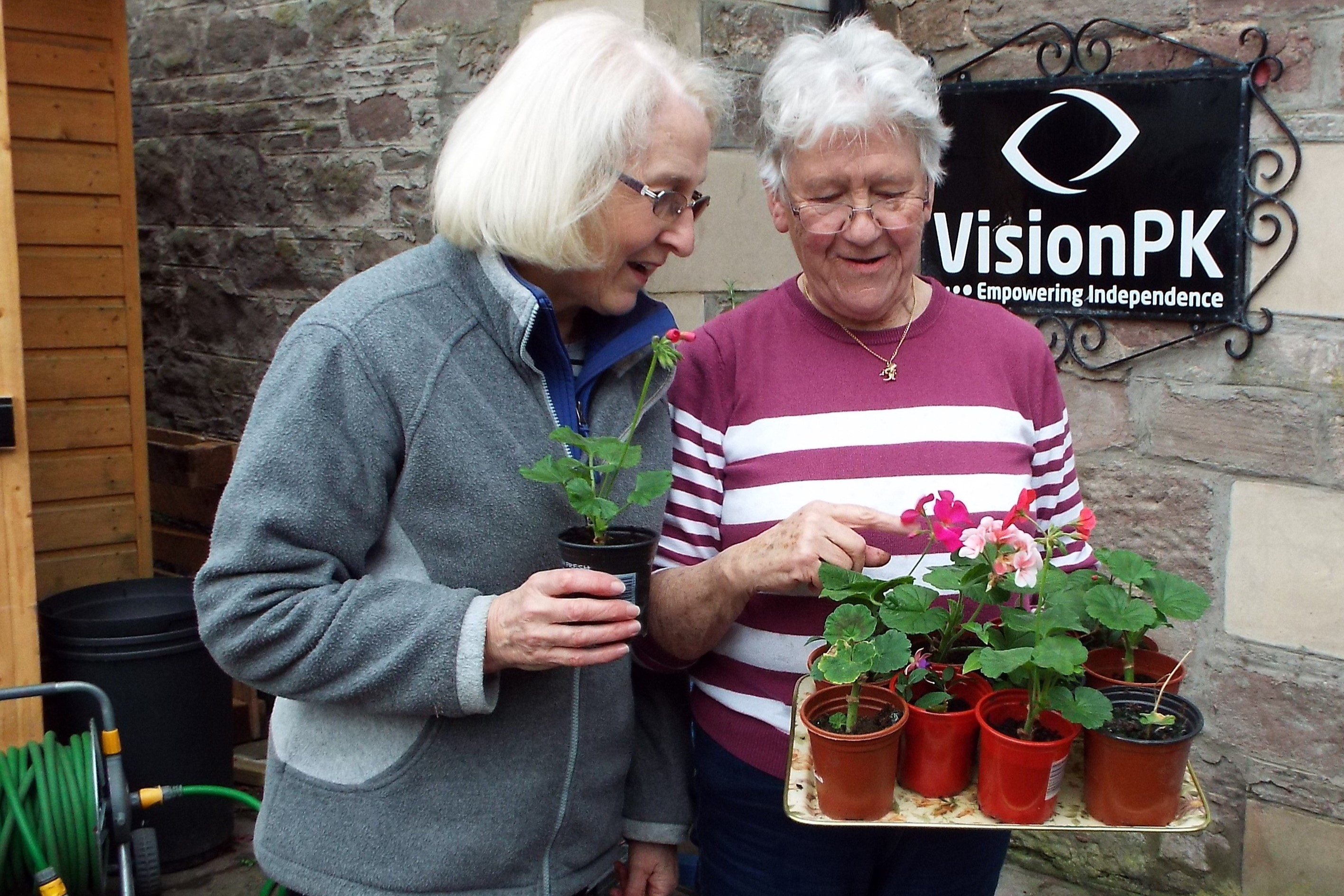 Two people looking at a plant from charity VisionPK